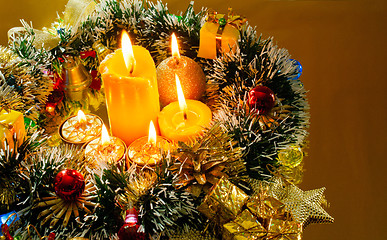 Image showing Christmas garland and burning candles over golden background