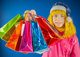 Image showing Teen girl holds a variety of colorful bags against blue background