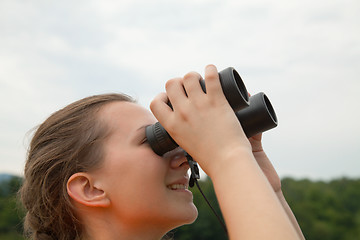 Image showing Young woman looking through binoculars