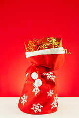 Image showing Christmas presents in the bag against red background