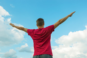 Image showing Young man staying with raised hands