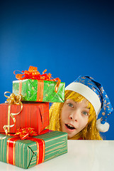 Image showing Surprised teen girl looking from behind the Christmas presents