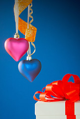 Image showing Two heart shaped toys hanging against blue background