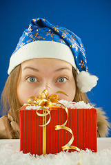 Image showing Surprised teen girl looking from behind the Christmas present