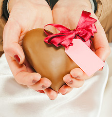 Image showing Hands holding a heart shaped chocolate candy 