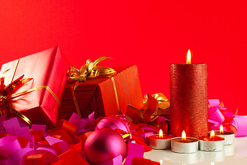 Image showing Christmas gifts and candles over red background