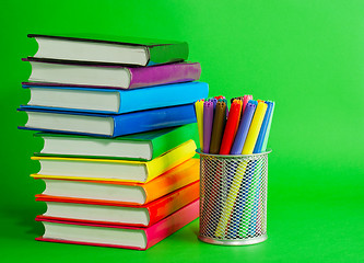 Image showing Stacks of colorful books and socket with felt pens