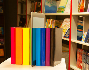 Image showing Row of colorful books and tablet PC reader in the book shop