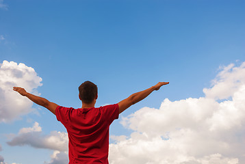 Image showing Young man staying with raised hands