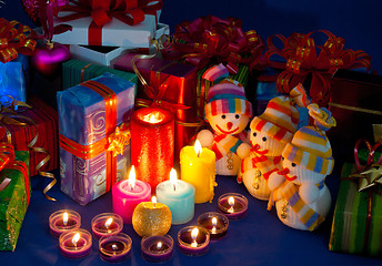 Image showing Three snowmen in front of the Christmas presents and burning can