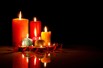 Image showing A lot of burning colorful candles against black background