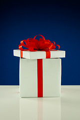 Image showing Open white box with present against blue background