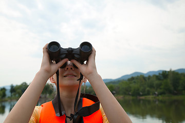 Image showing Young woman looking through binoculars