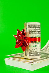 Image showing Roll of US dollars tied up with ribbon on the stack of bills