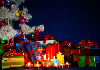 Image showing Christmas presents and burning candles against blue background