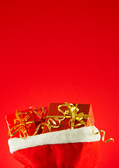 Image showing Christmas presents in the bag against red background