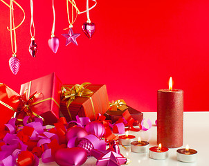 Image showing Christmas gifts and candles over red background