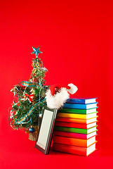 Image showing Electronic book reader with stack of books against red background