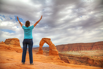 Image showing Woman with raised hands in front of Delicate Arch