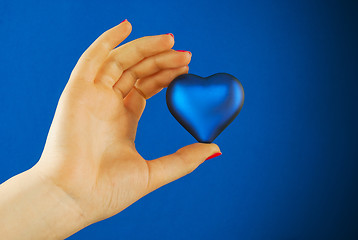 Image showing Hand holds a heart shaped gift against blue background