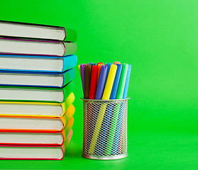 Image showing Stack of colorful books and socket with felt pens