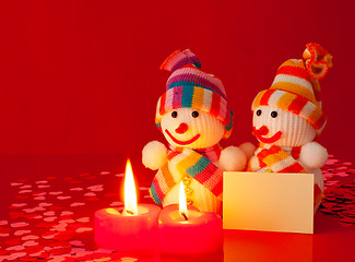 Image showing Three snowmen with two burning heart shaped candles