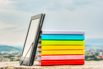 Image showing Stack of colorful books with electronic book reader