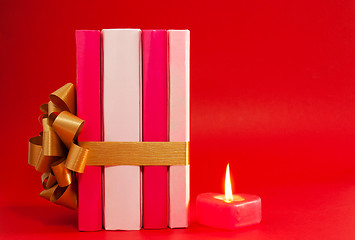 Image showing Row of books tied up with ribbon and burning candle