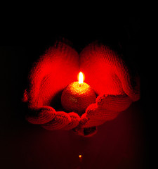 Image showing Human hands hold burning candle against dark background