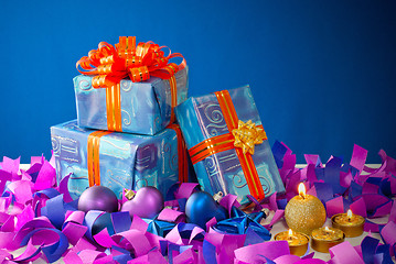 Image showing Christmas gifts and candles over blue background