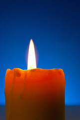 Image showing Close up of a burning candle against blue background