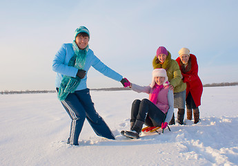 Image showing Four happy ladies sledding at winter time