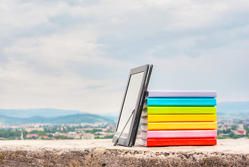 Image showing Stack of colorful books with electronic book reader