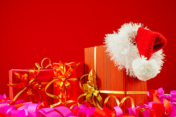 Image showing Christmas presents with Santa's hat against red background