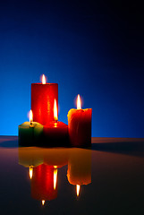 Image showing Four burning colorful candles against black background