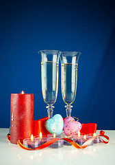 Image showing Two wineglasses and burning candles against blue background