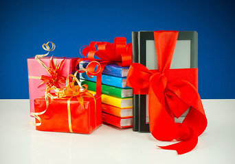 Image showing Christmas presents with electronic book reader against blue background