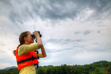 Image showing Young woman looking through binoculars