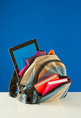 Image showing Backpack with colorful books and pablet PC on the blue backgroun