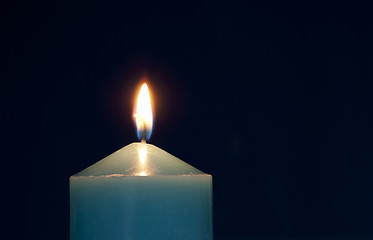 Image showing Close up of burning candle against dark blue background