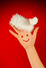 Image showing Human's palm with smile on it wearing Santa's hat