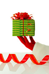 Image showing Santa's hand holding a Christmas present against white backgroundSanta's hand holding a Christmas present against white background