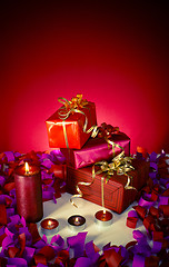 Image showing Christmas gifts and candles over red background