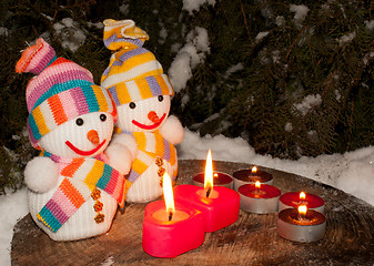 Image showing Two snowmen with two burning heart shaped candles