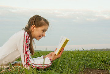 Image showing Teen girl reading a book at a field