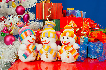 Image showing Three snowmen in front of the Christmas presents over the blue b