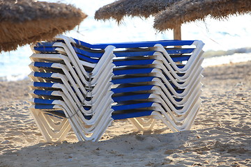 Image showing Stack of recliner chairs on a beach