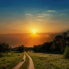 Image showing dramatic sunset over road in wood