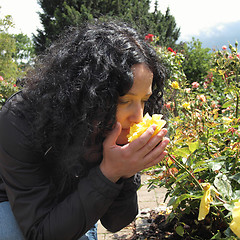 Image showing Pretty brunette smelling roses