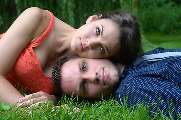 Image showing Young couple laying on the grass with the woman's head resting o